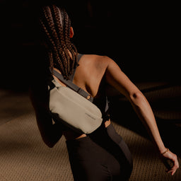 A woman running with a Sand crossbody on her back