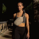 A woman wearing a Sand Crossbody across her front as she is directly infront of the camera