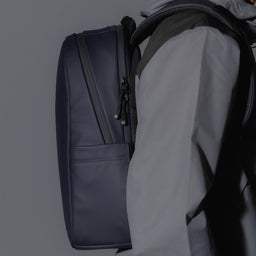 A studio shot of an Everyday Backpack 15L in Midnight Blue showing a close up of the bag on a mans back