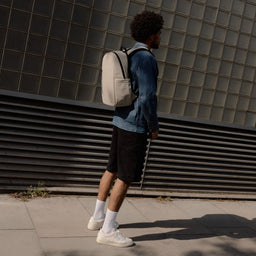A man standing in the street wearing an Everyday Backpack 20L in Sand on his back