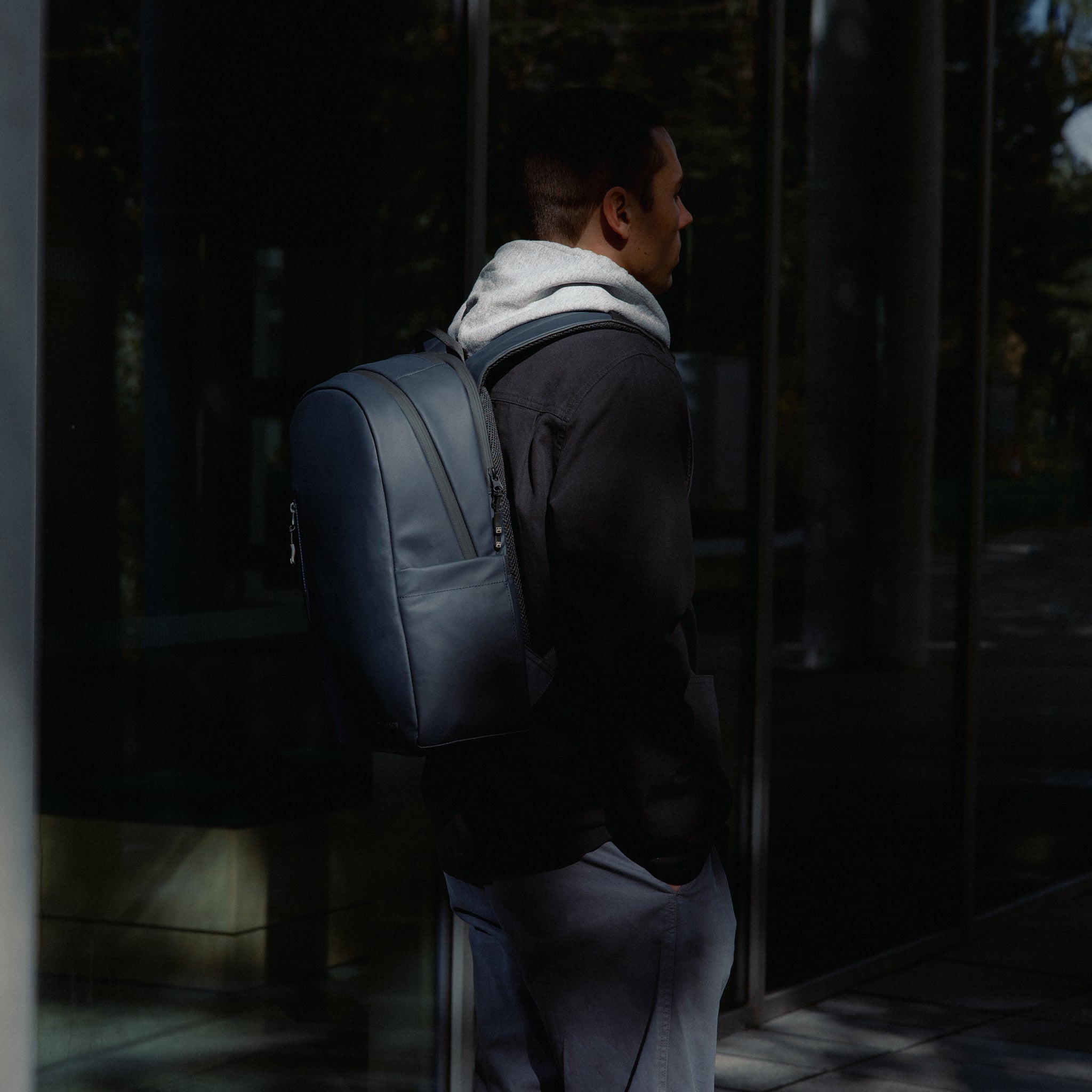 A man standing in the sunshine with an Everyday Backpack in Midnight Blue on his back
