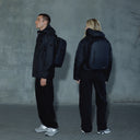 A man and woman standing wearing an Everyday Backpack in Midnight Blue on their backs