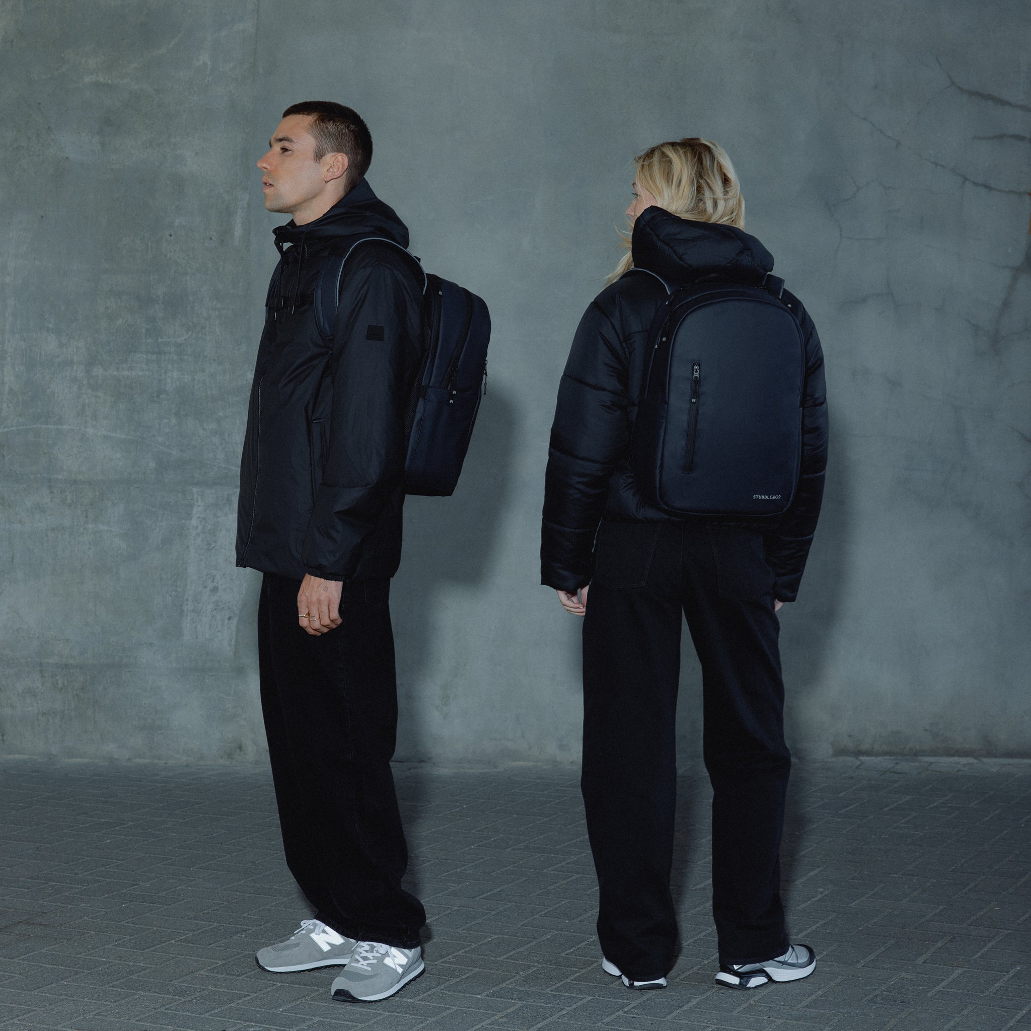 A man and woman standing wearing an Everyday Backpack in Midnight Blue on their backs