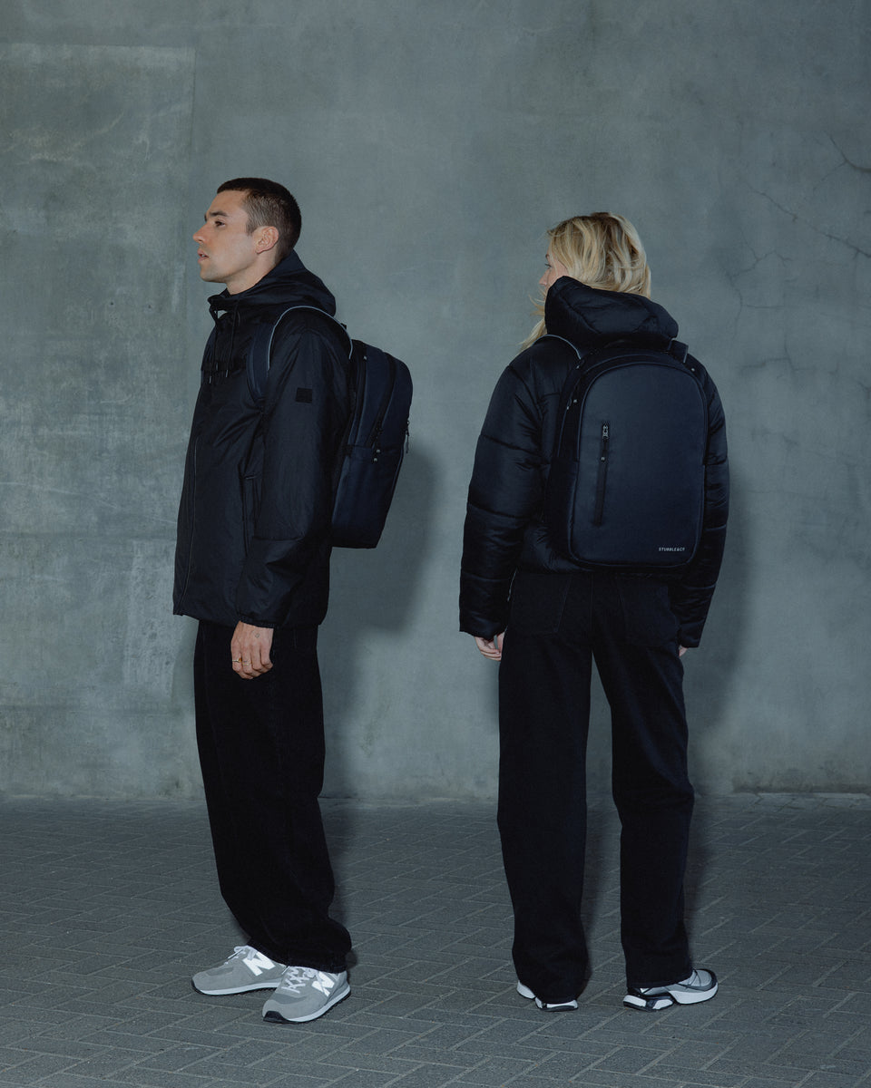 A man and woman wearing an Everyday Backpack on their backs in Midnight Blue