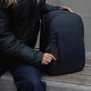 A woman placing a phone in the front pocket on an Everyday Backpack in Midnight Blue