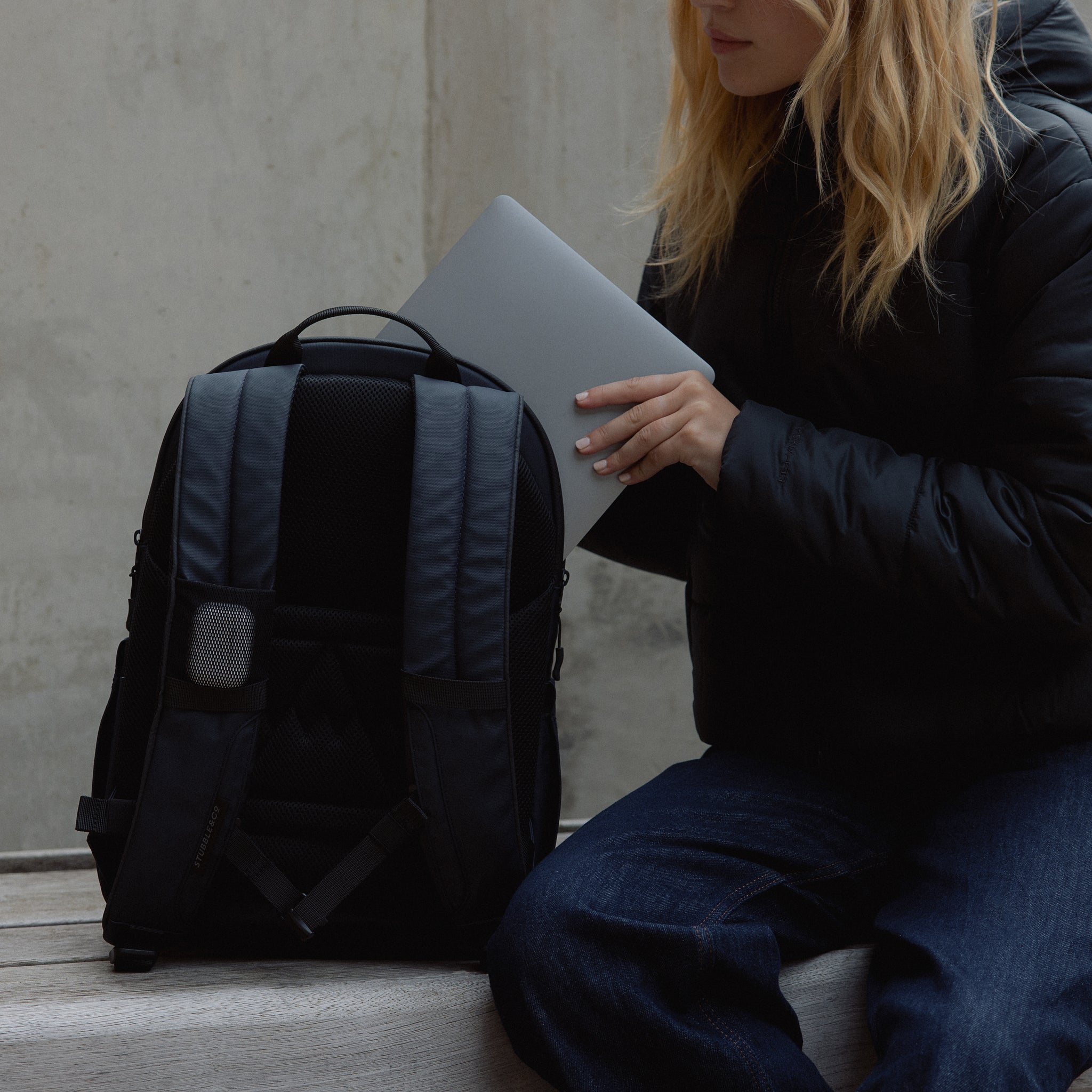A woman placing a laptop into the laptop compartment in an Everyday Backpack in Midnight Blue