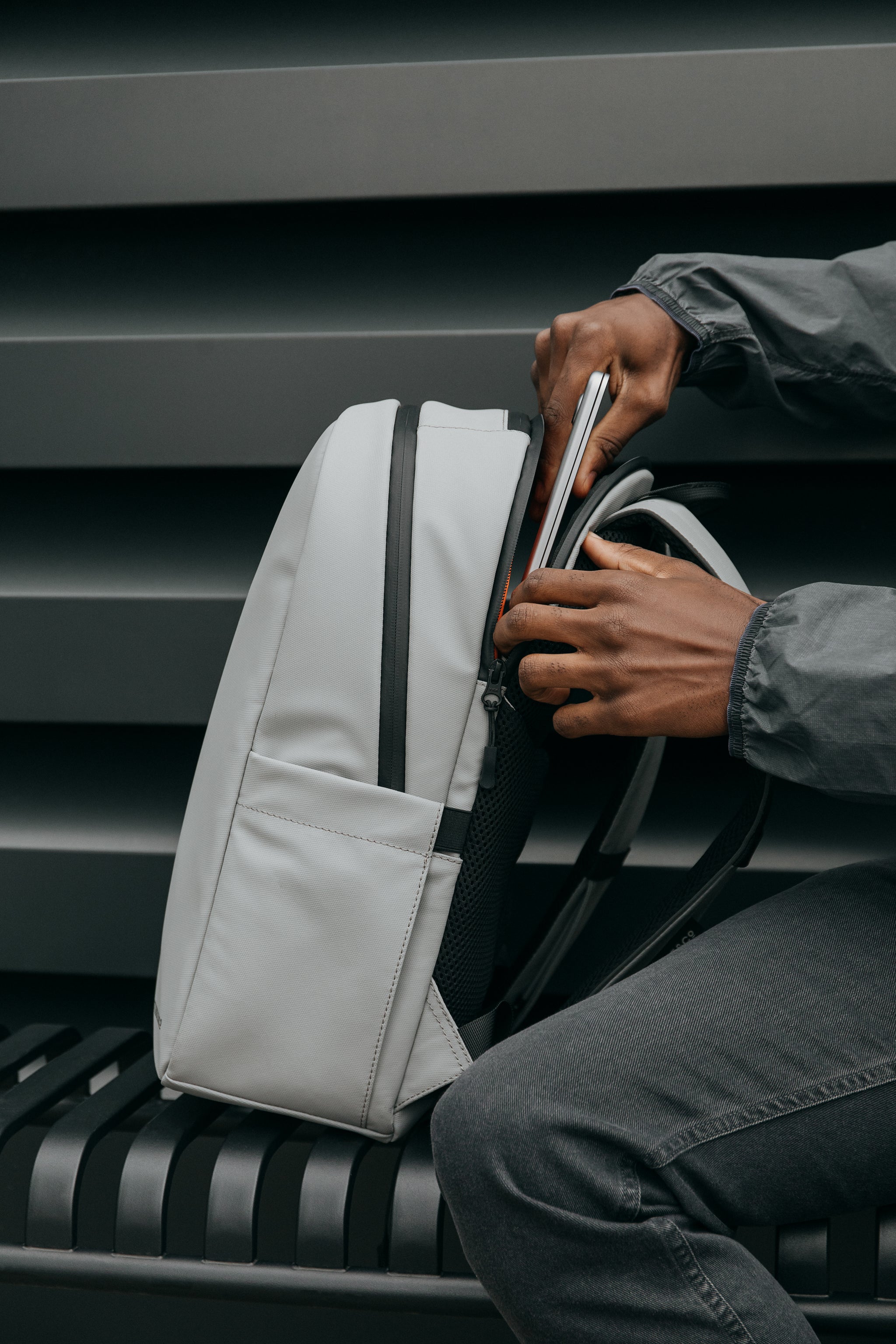 Man putting a laptop in a grey backpack