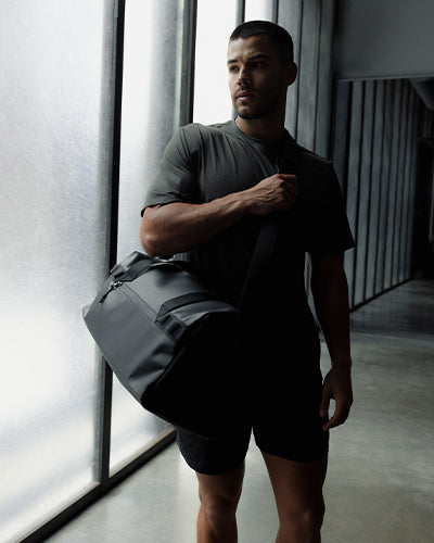 A man wearing a gym duffel 25l in black on his shoulder
