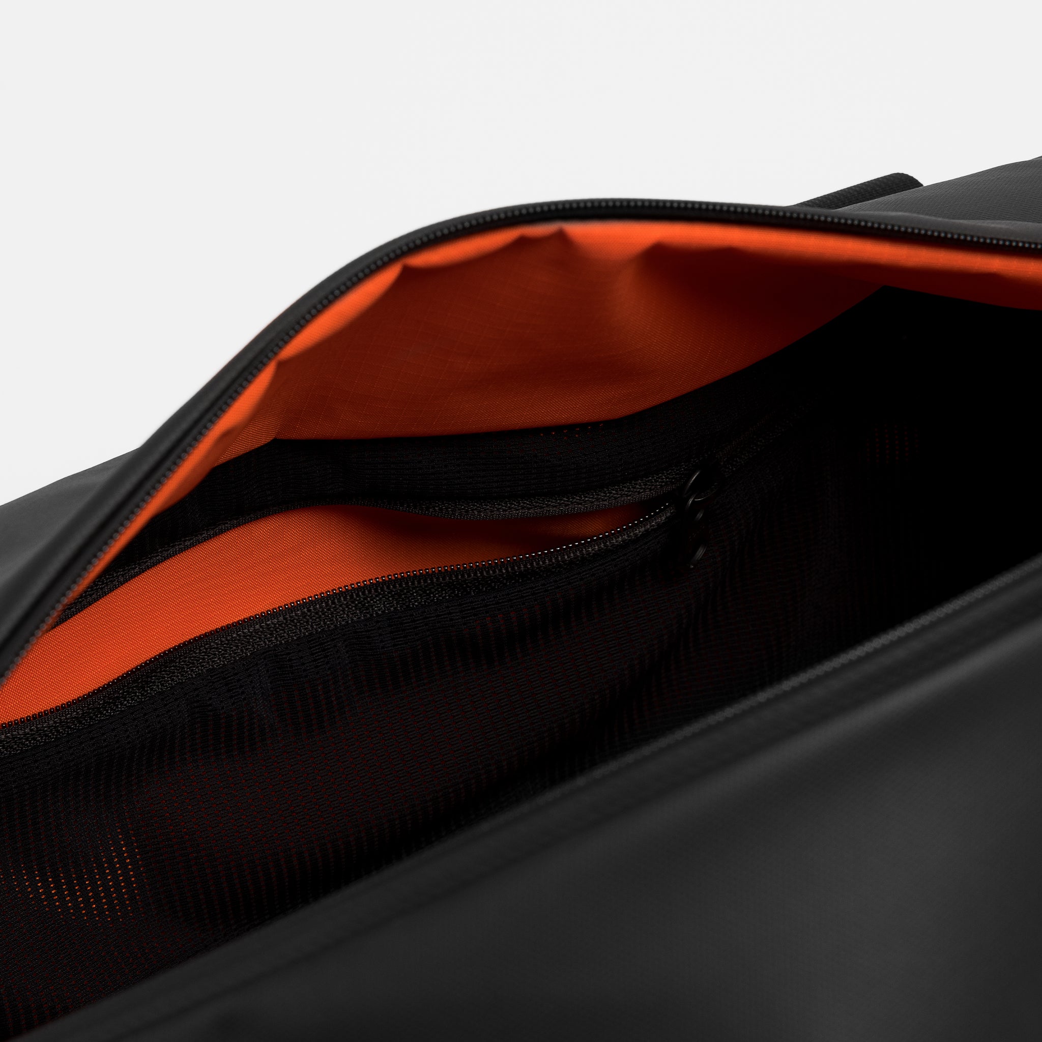 A studio shot of the internal zipped mesh pocket inside the Gym Duffel 25L in All Black
