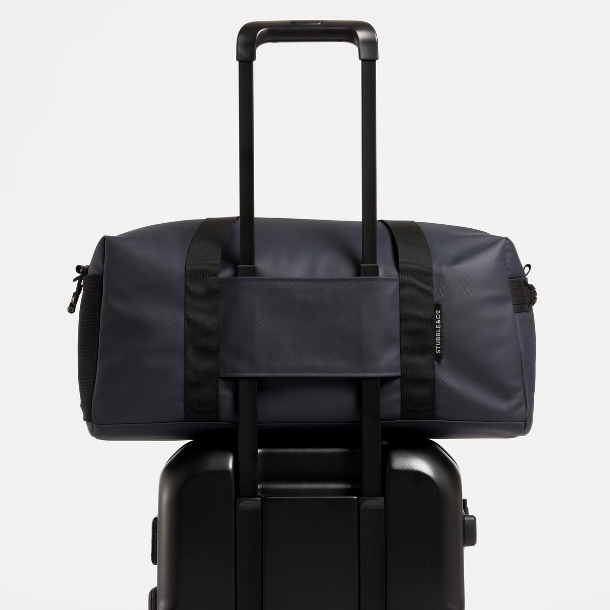 A studio shot of the Midnight Blue Gym Duffel on a suitcase using a trolley sleeve