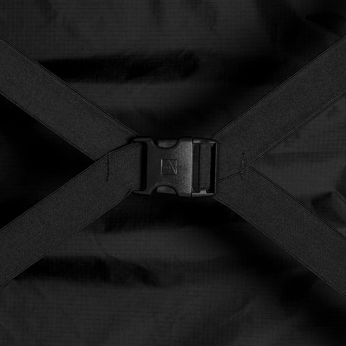 Close-up of a black clip buckle connecting compression straps inside a suitcase.