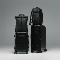A studio shot of the Hardshell Pro range in All Black with the Roll Top and Hybrid Backpack on the trolley sleeve