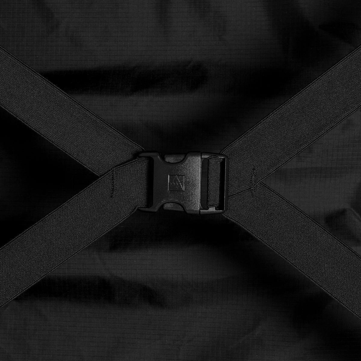 Close-up of a black clip buckle connecting black elastic compression straps inside a suitcase.