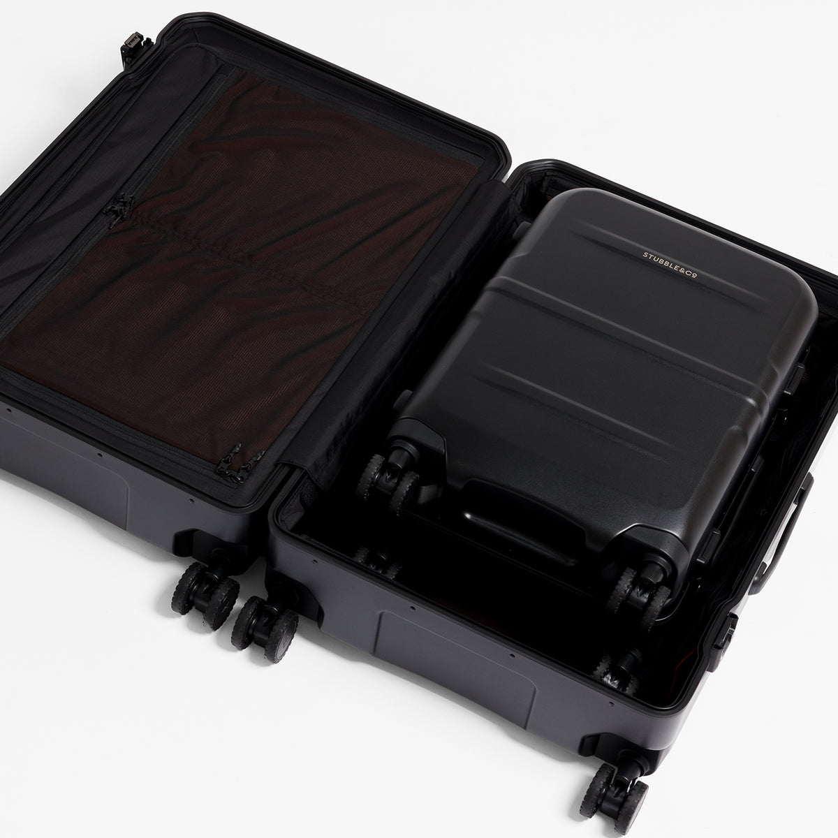 A black hard-shell suitcase shown open, with a smaller matching black suitcase nested inside on a clean white background.