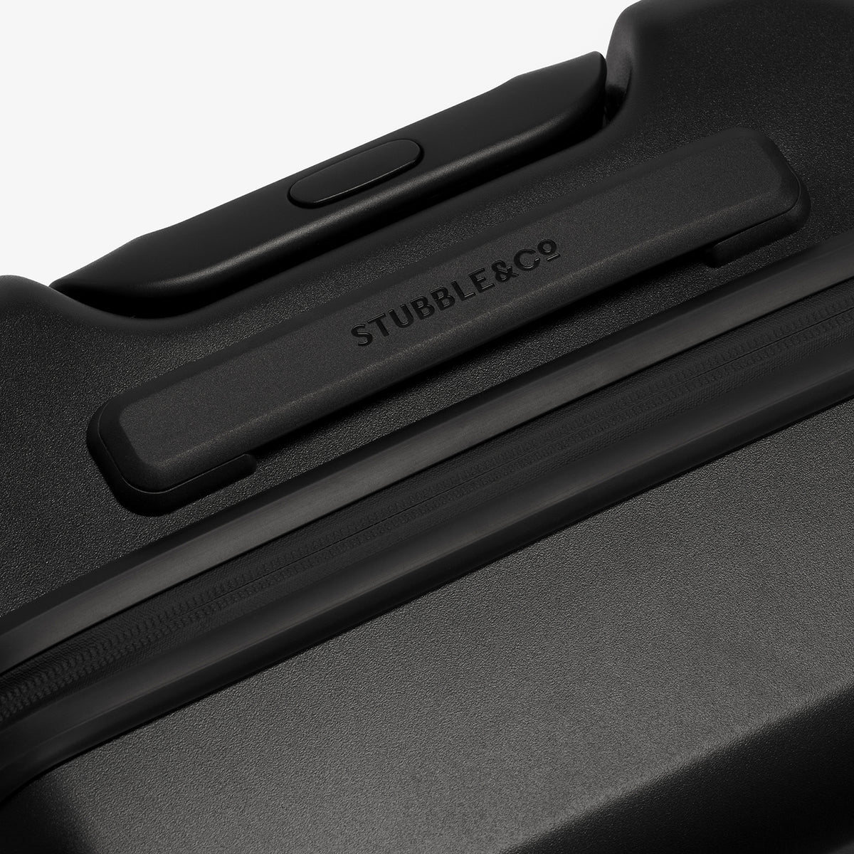 Close-up of a black hard-shell suitcase handle with the debossed brand name STUBBLE&CO visible on the side, set against a clean white background.