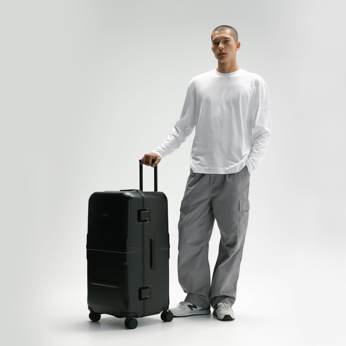 A man with the Hardshell Pro Trunk 100L in All Black