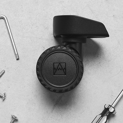 Suitcase spinner wheel with the mountain logo on its hub cap, beside an Allen key, screwdriver and screws.