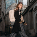 A woman crossing a street in London looking at the camera wearing a Tonal Sand Hybrid 20L on her back