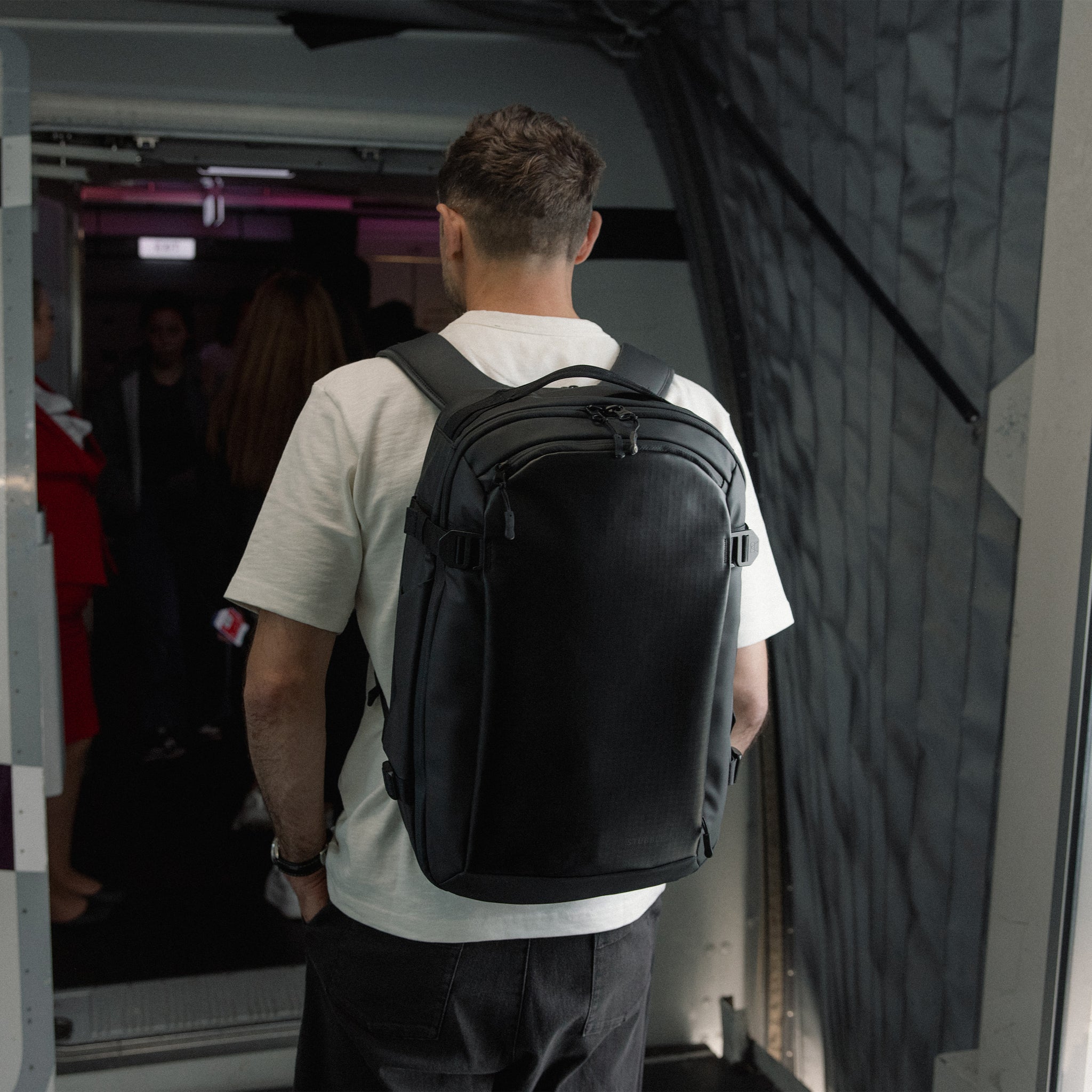 A man boarding a plane wearing a Hybrid Backpack on his back