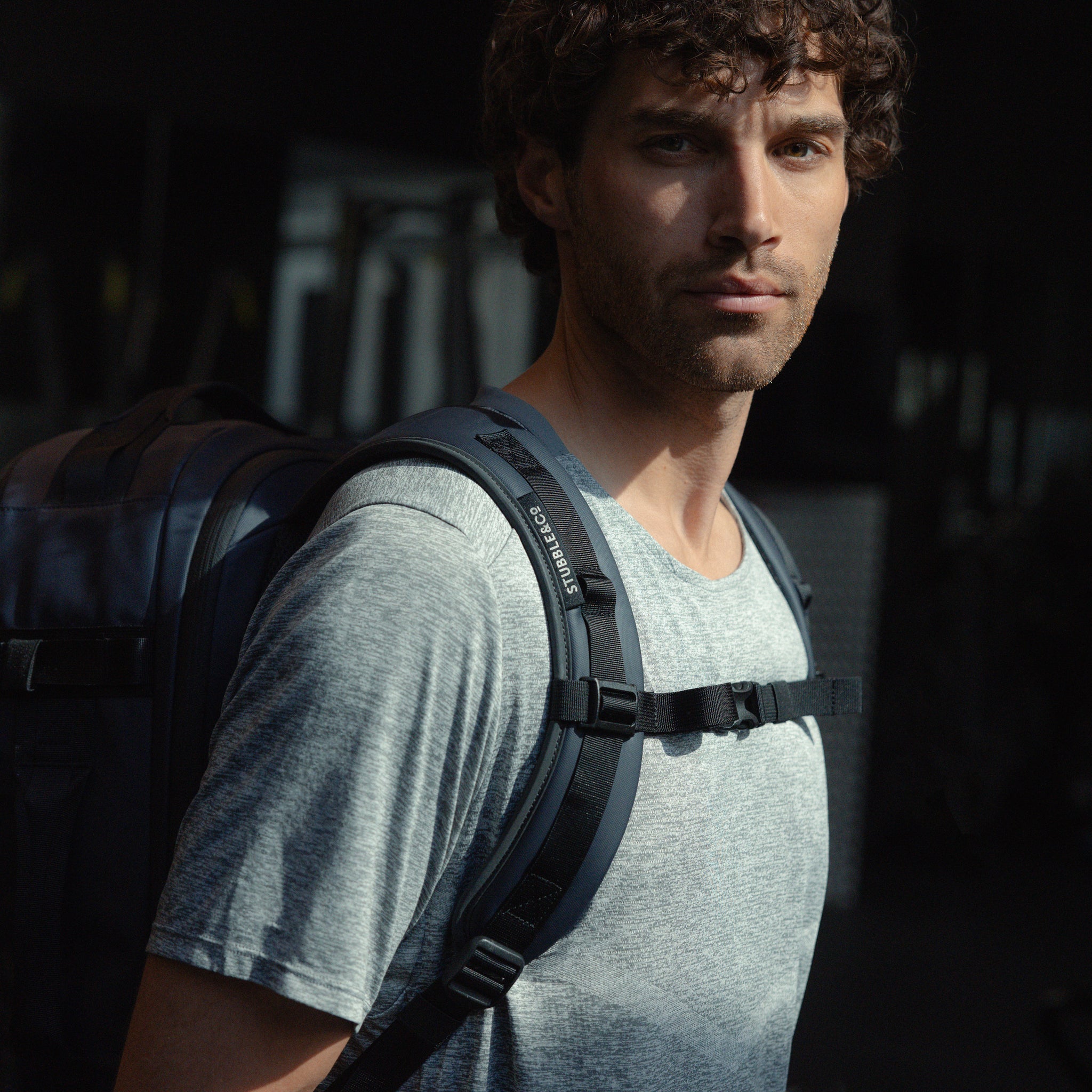 A man looking into the camera showing the chest-straps of the Hybrid Backpack 30L in Midnight Blue done up across his chest
