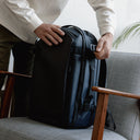 A man doing up the g-hook compression strap on the side of a Midnight Blue Hybrid Backpack 30L