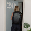 A woman entering an aprtment with a Midnight Blue Hybrid 30L on her back