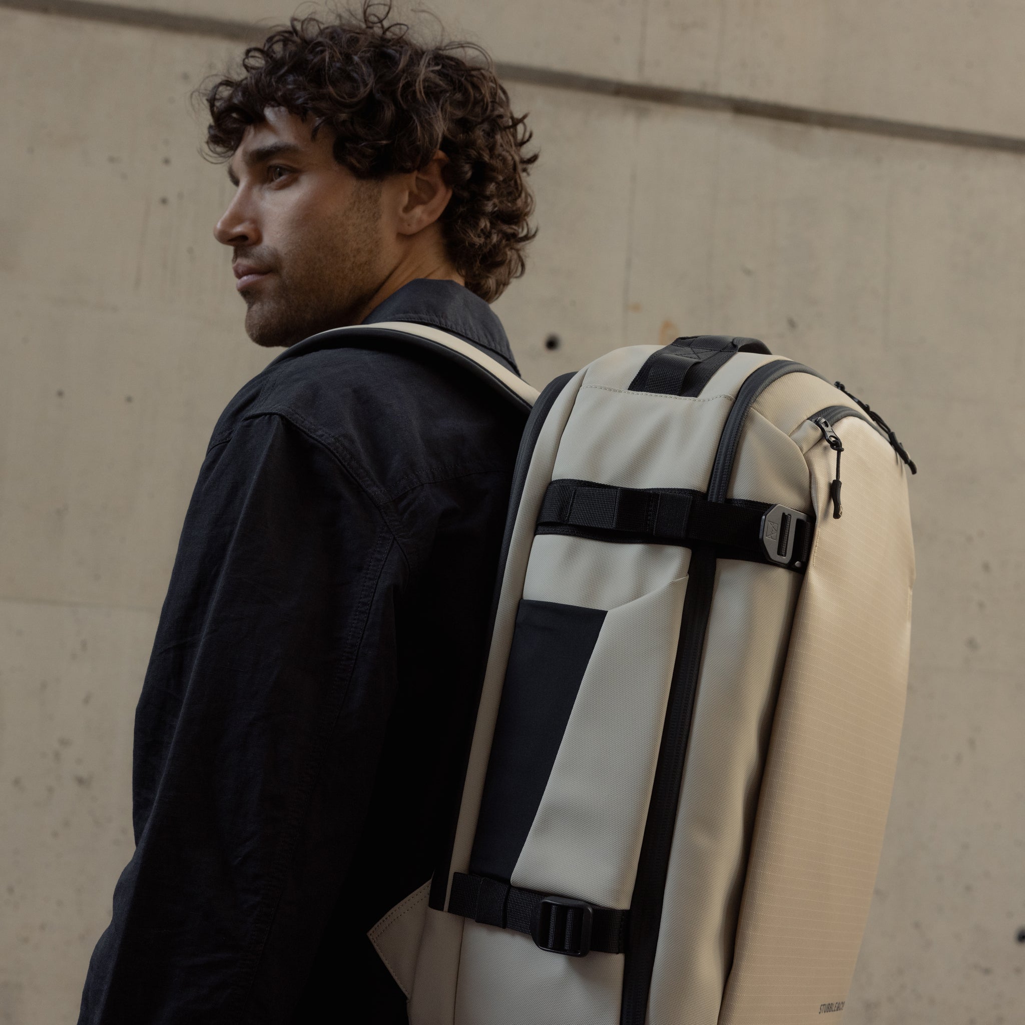 A man wearing a Hybrid Backpack 30L in Sand on his back