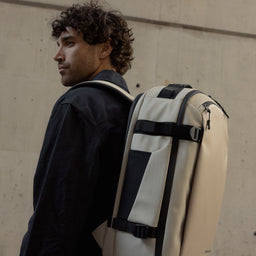 A man wearing a Hybrid Backpack 30L in Sand on his back