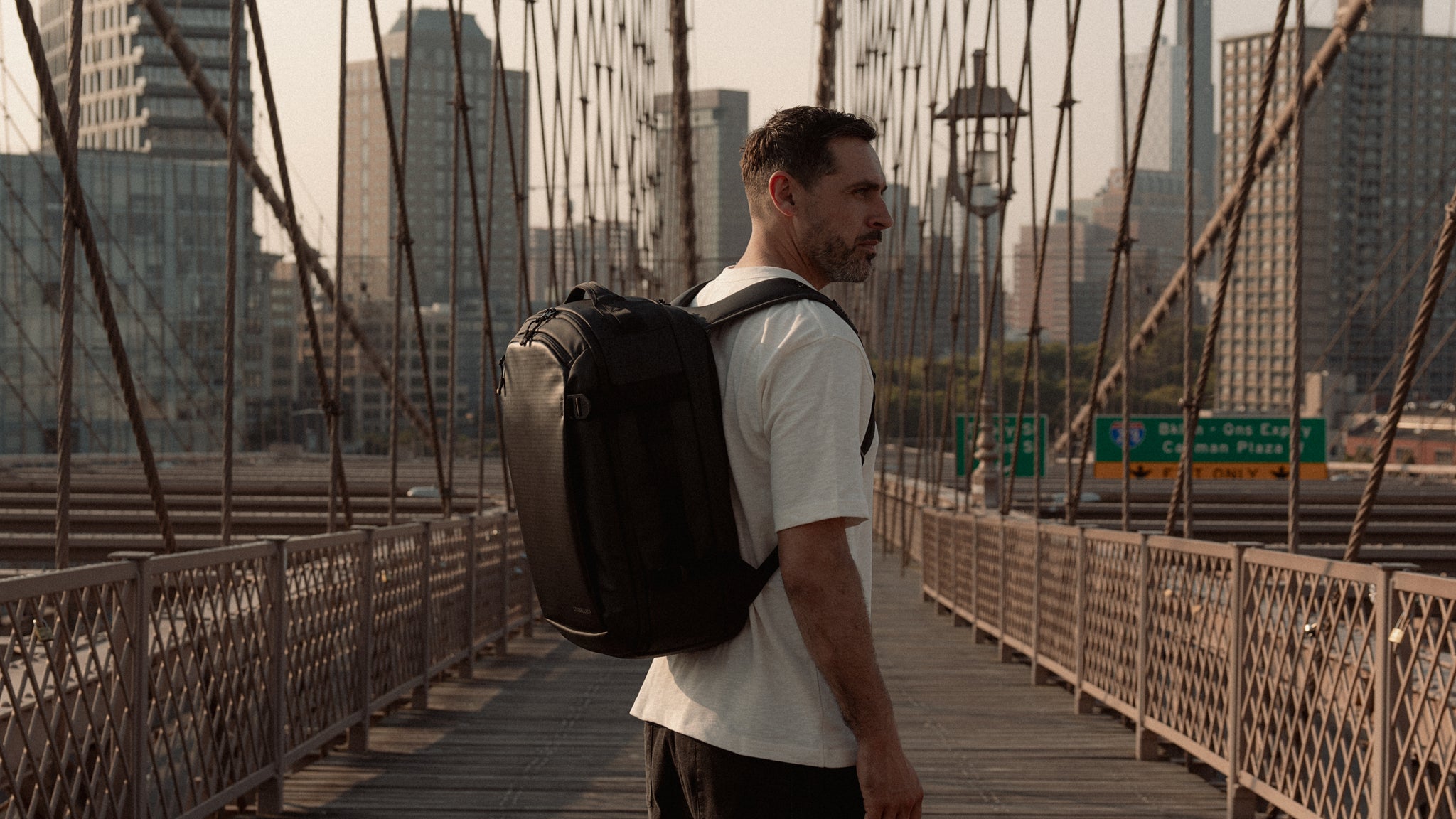 a man standing on a bridge in New York wearing a Hybrid Backpack 30L on his back