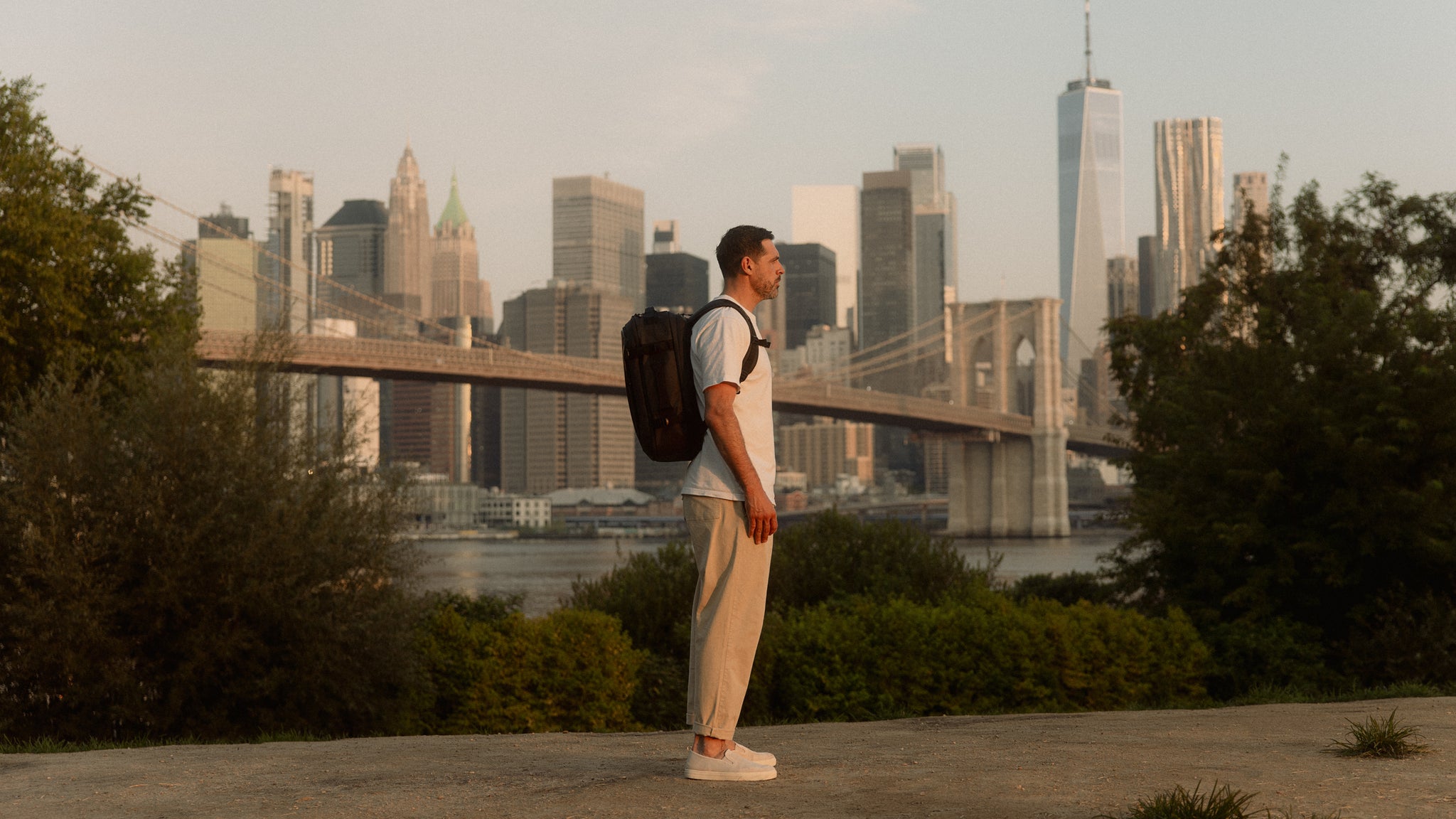 A man standing in front of the new york city scape with a hybrid backpack 30l on his back