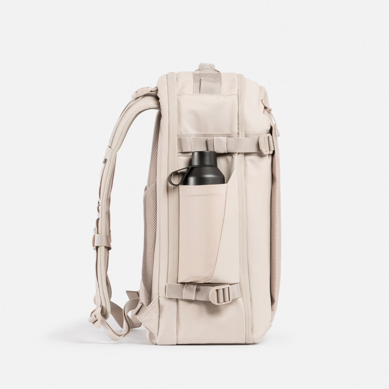 A studio shot of the elasticated bottle pocket on the side of the Tonal Sand Hybrid Backpack 30L