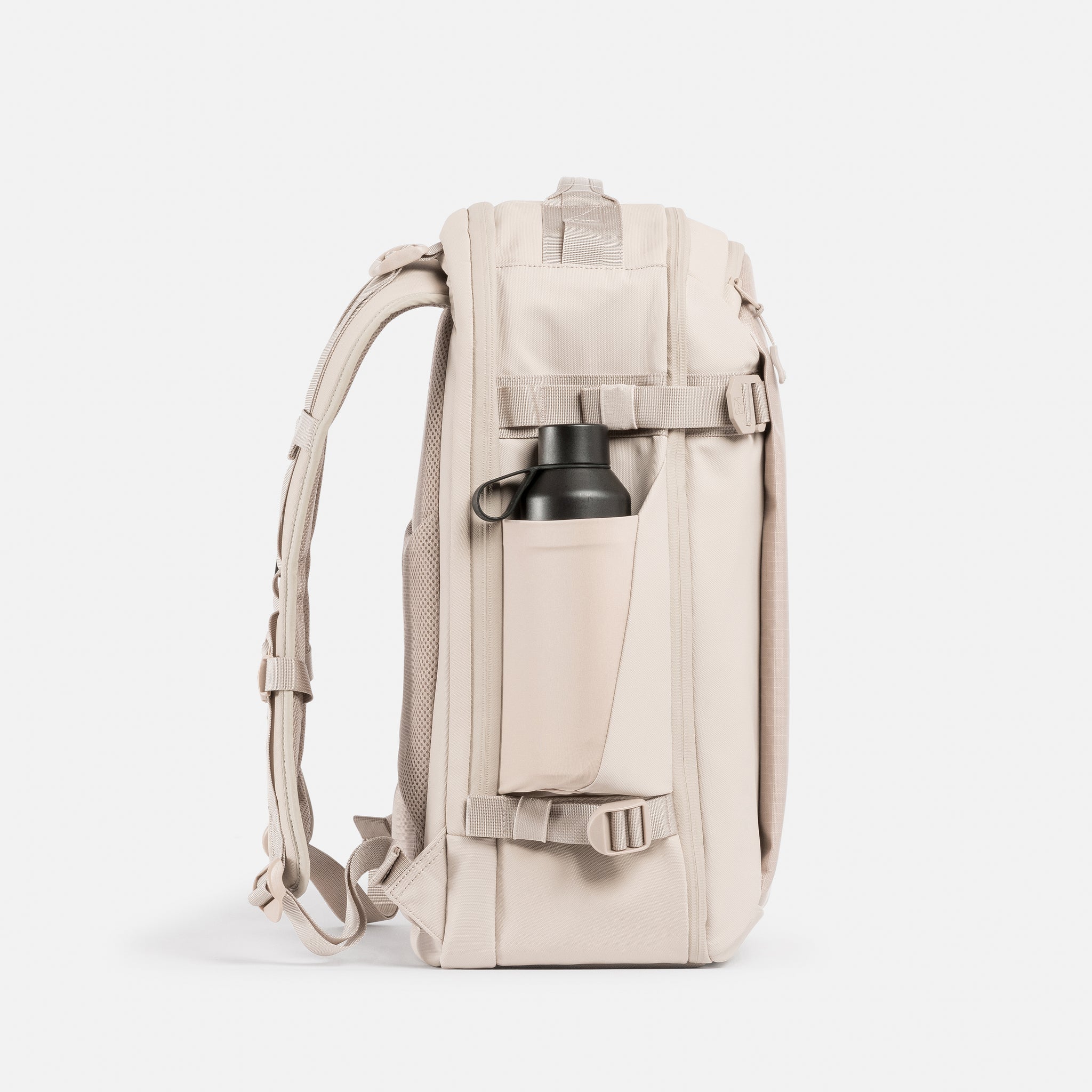 A studio shot of the elasticated bottle pocket on the side of the Tonal Sand Hybrid Backpack 30L