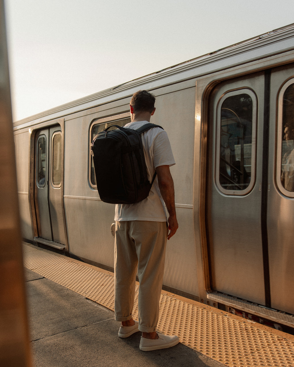A man wearing a hybrid backpack 30l on his back on a subway platform in new york