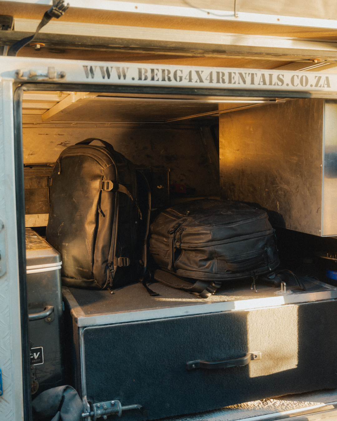 Black backpacks in boot of open truck whilst on road trip in Namibia