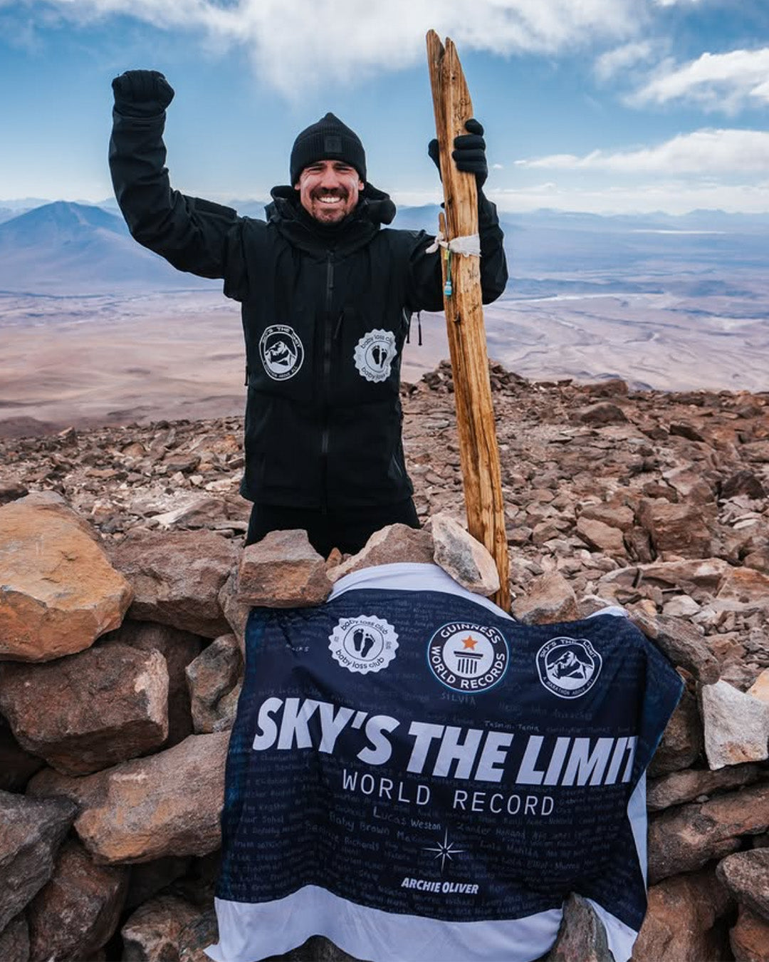 Joshua Patterson on a mountain top with a banner celebrating a world record.