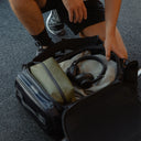 A man packing a Kit Bag 30L in Midnight Blue with gym equipment