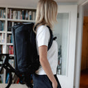 A woman facing side on wearing a Kit Bag 30L in Midnight Blue on her back