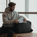 A man putting a laptop into an All Black Kit Bag 30L