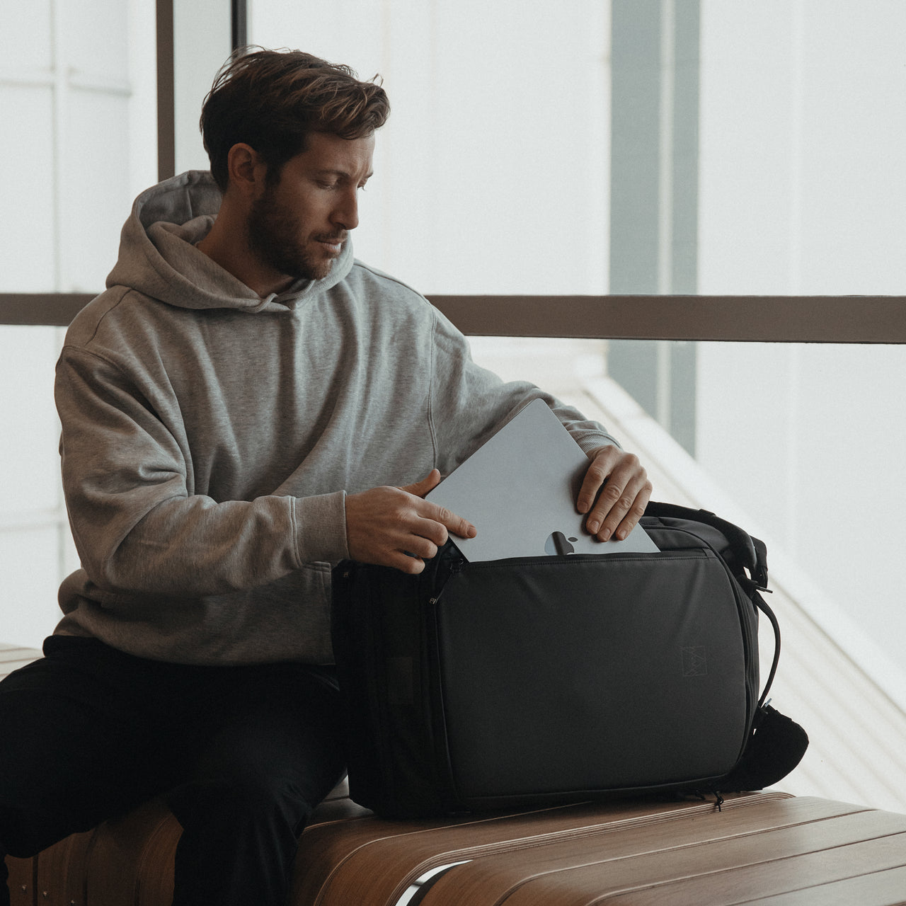 A man putting a laptop into an All Black Kit Bag 30L