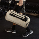 A man holding a Kit Bag 30L like a duffel down by his side in Sand