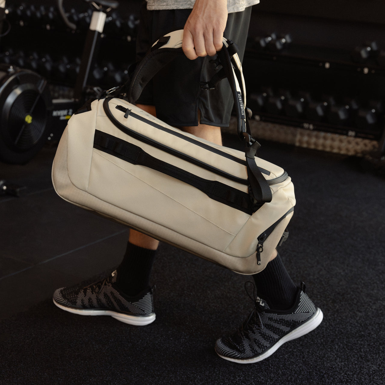 A man holding a Kit Bag 30L like a duffel down by his side in Sand