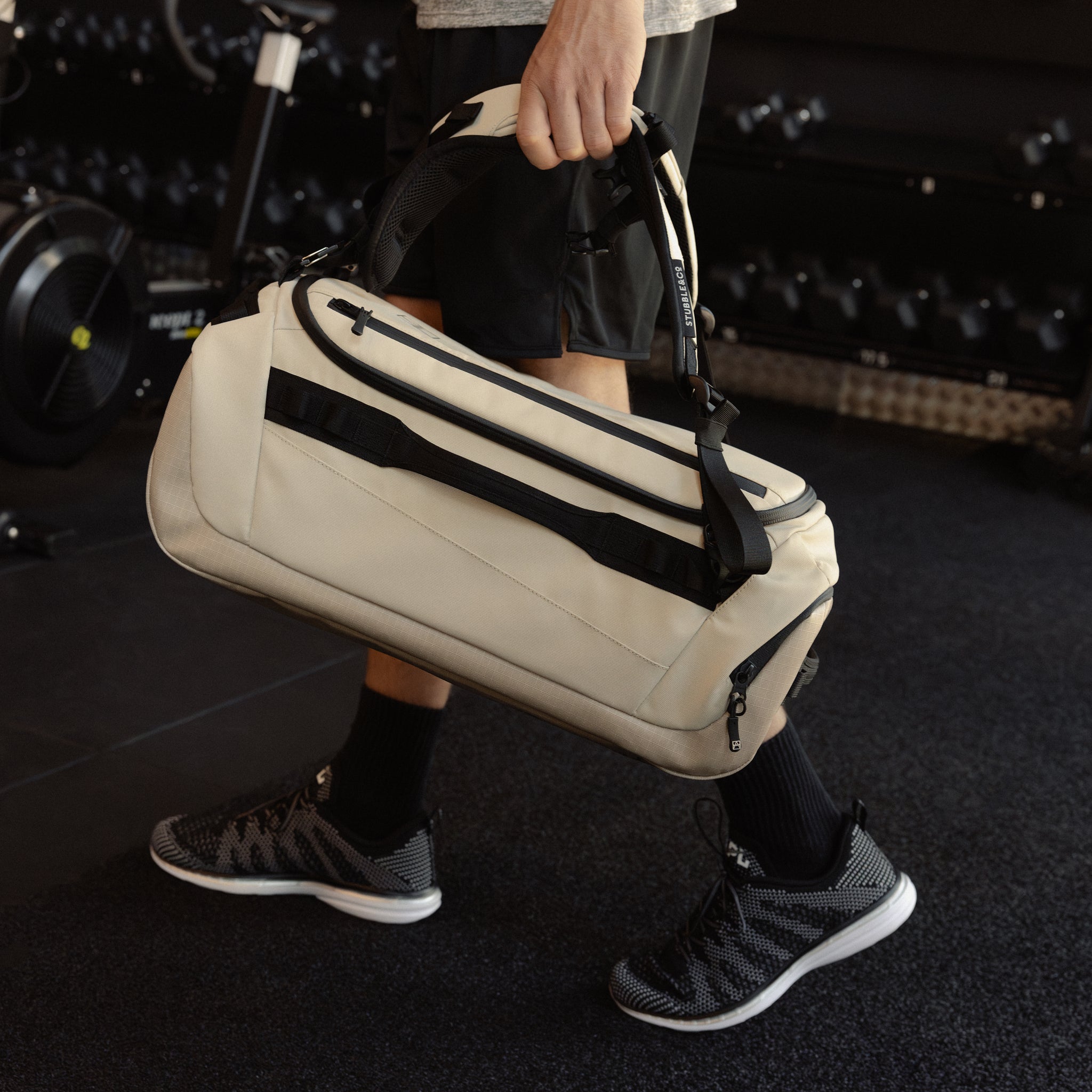 A man holding a Kit Bag 30L like a duffel down by his side in Sand