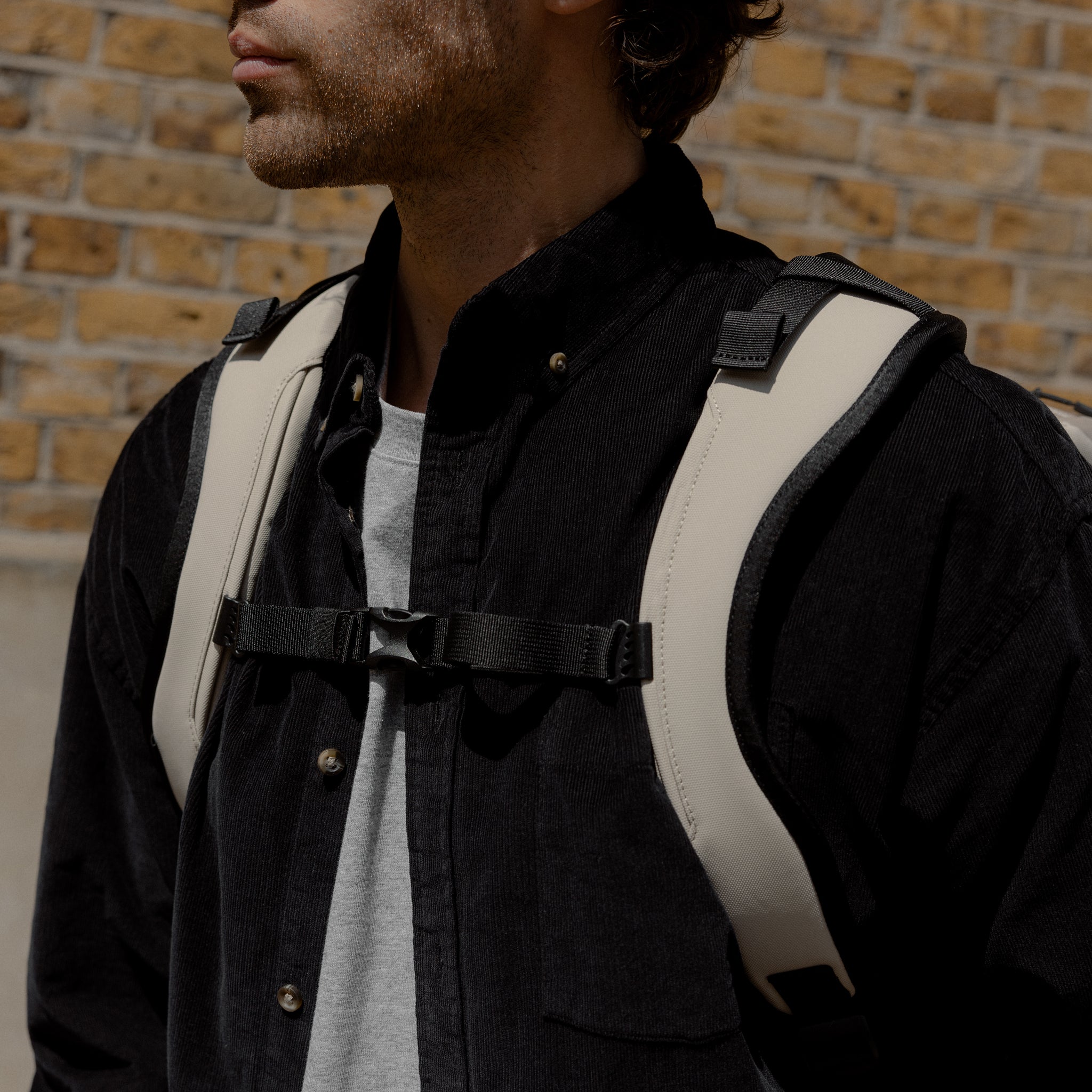 A close up of the chest straps done up on a man wearing a Kit Bag 30L in Sand