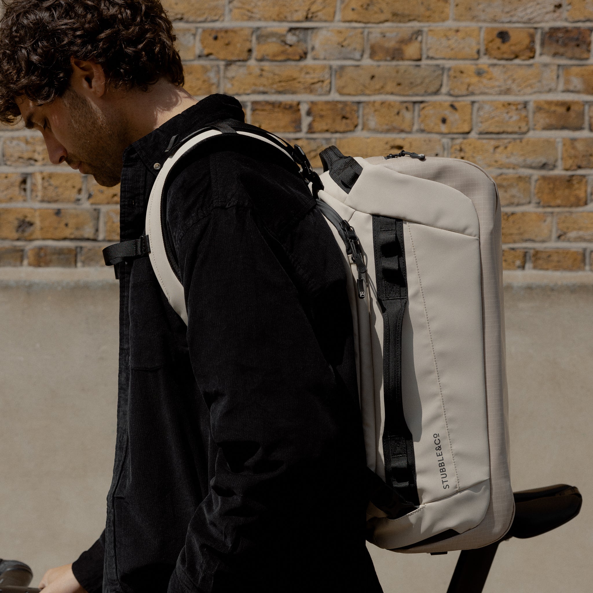 A man standing side on wearing a Kit Bag 30L in Sand on his back