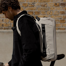 A man standing side on wearing a Kit Bag 30L in Sand on his back
