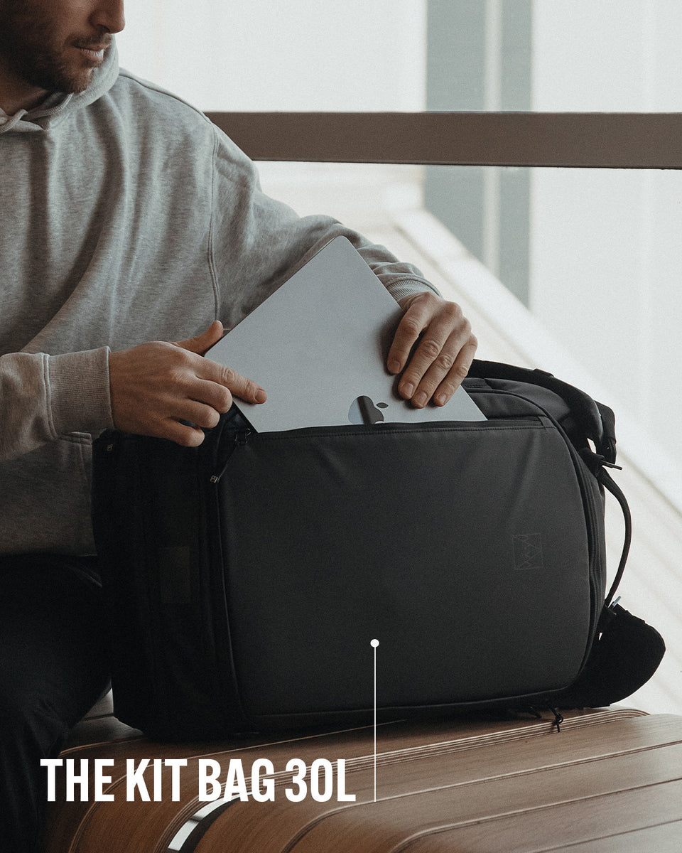 A man putting a laptop into his kit bag 30l with product name annotated