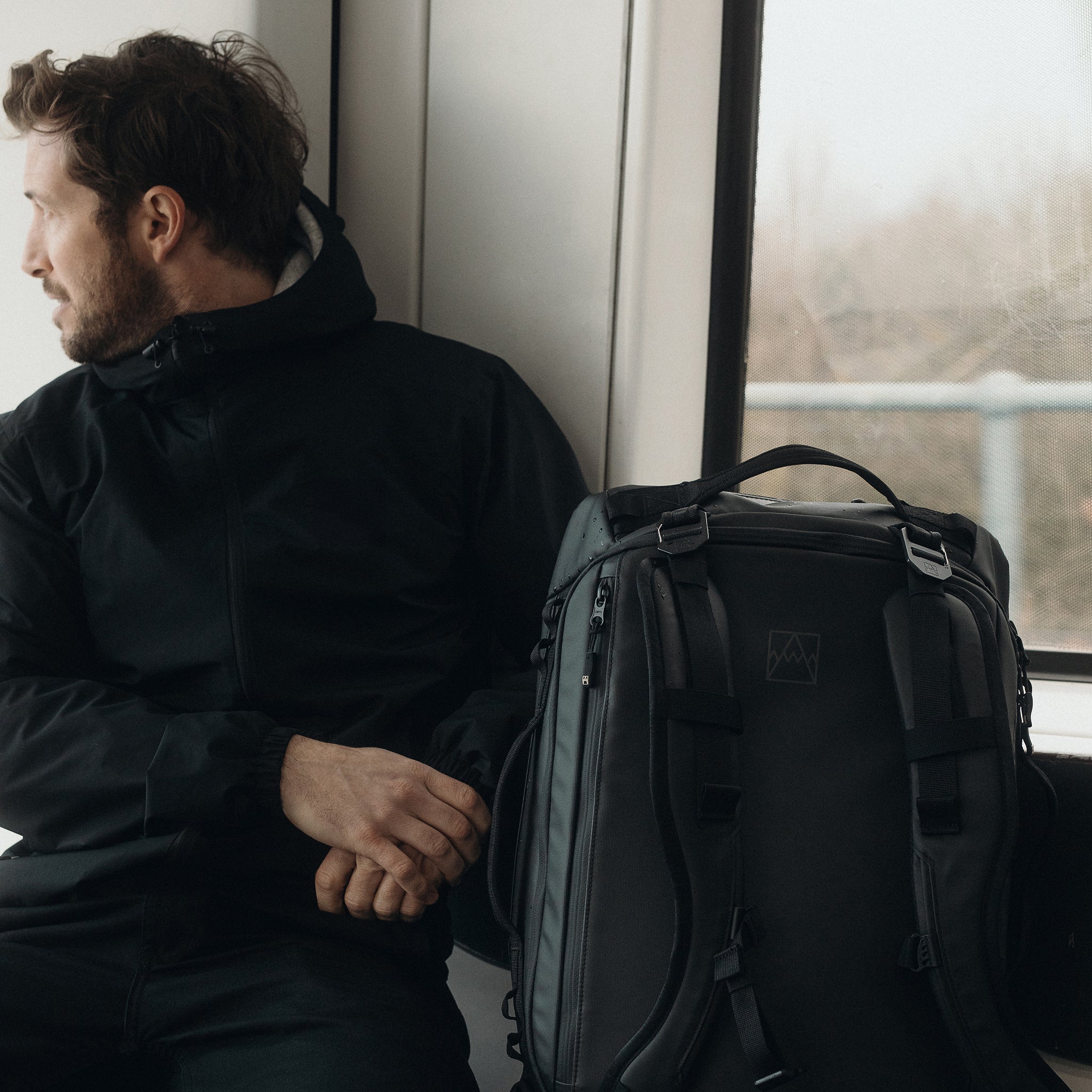 A man sitting on the train with an All Black Kit Bag 30L on the seat next to him
