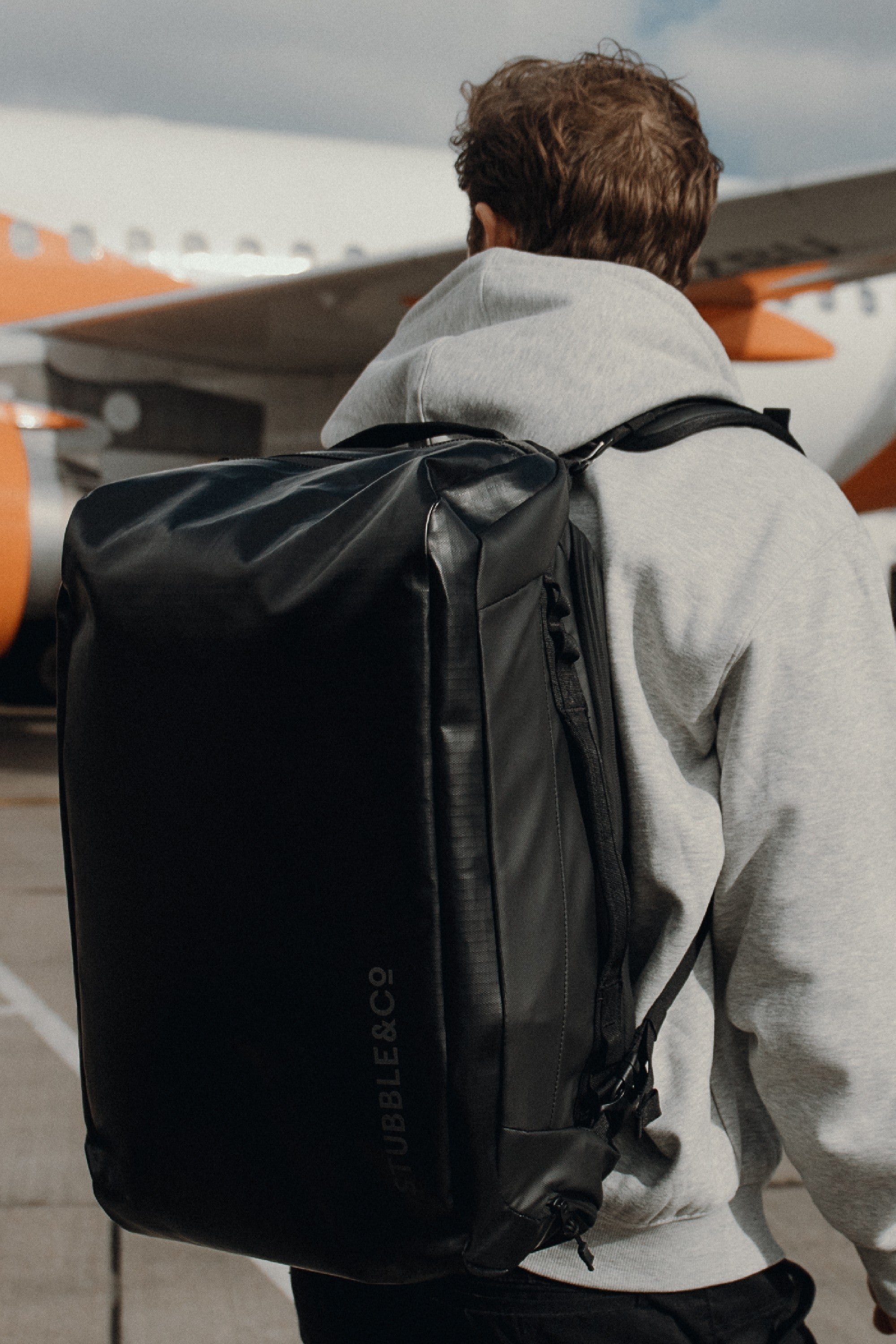 Man wearing 30l backpack by a plane