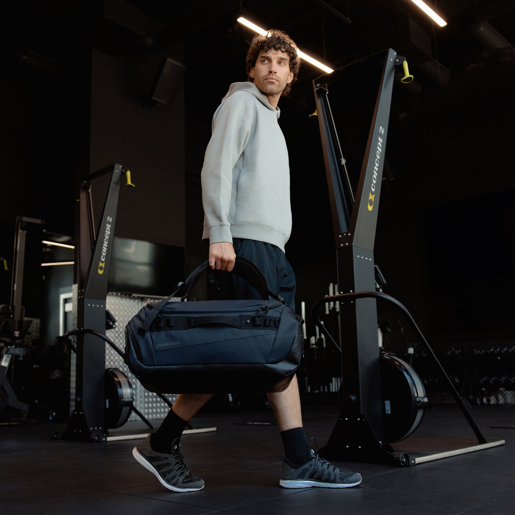 A man carrying a Kit Bag 40L in Midnight Blue down by his side like a duffel bag
