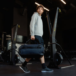 A man carrying a Kit Bag 40L in Midnight Blue down by his side like a duffel bag